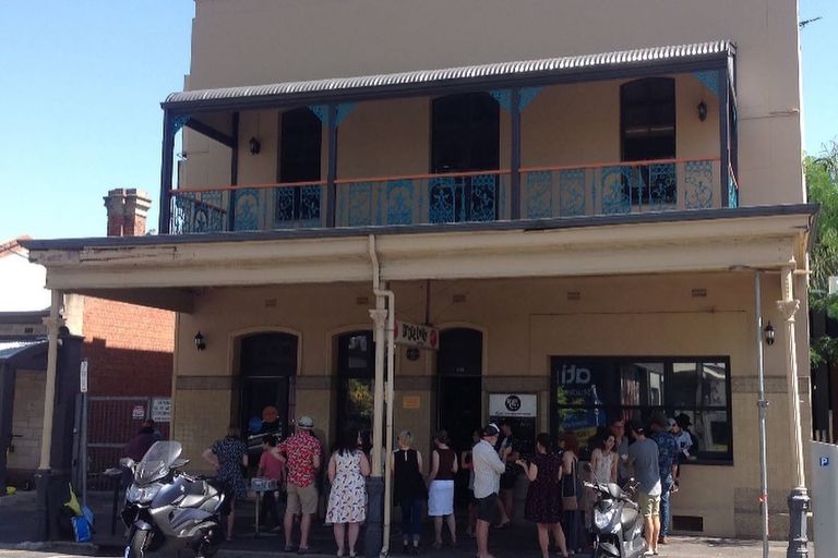 Exterior view of the historic Grace Emily Hotel in Adelaide, featuring a double-storey verandah and people gathered outside the pub entrance.